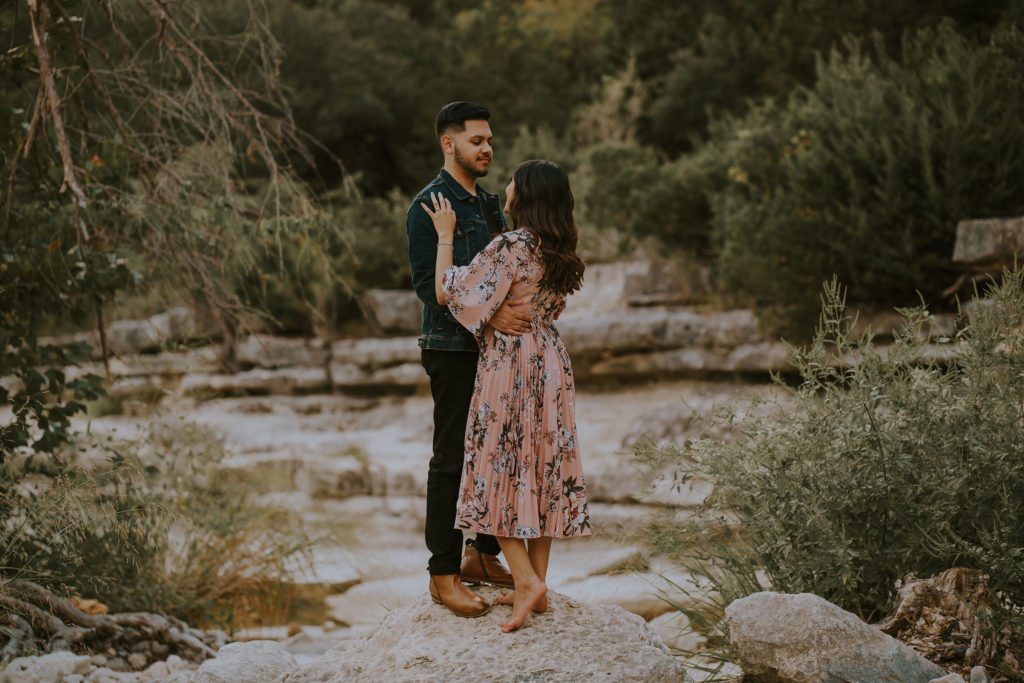 A couple standing on a rock at Bull Creek in Austin, Texas.